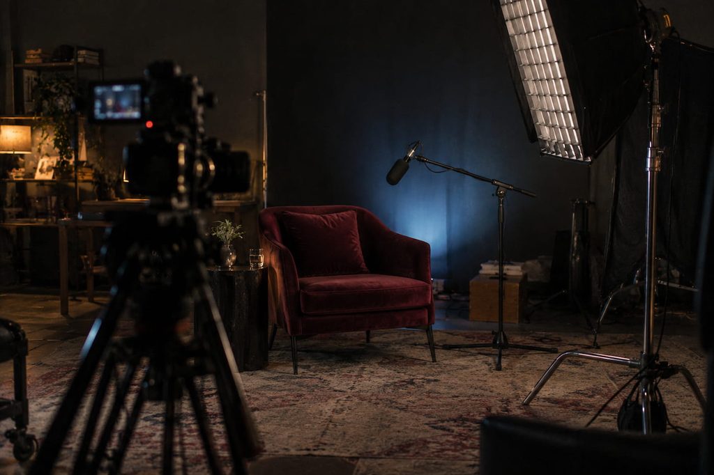 Interview set with a burgundy armchair, video camera and studio lights