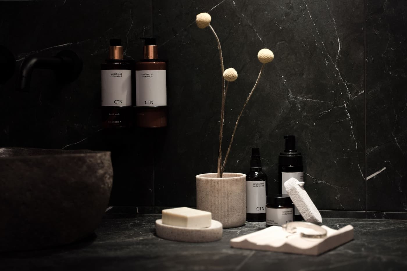 Minimalist skincare bottles on a dark stone bathroom counter